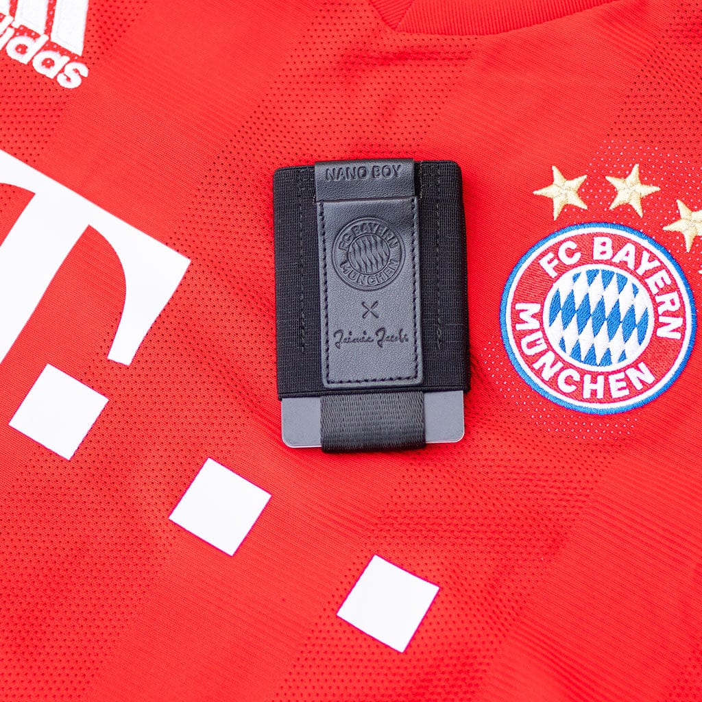 nano boy aus der fc bayern muenchen edition liegt auf einem bayern trikot